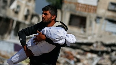A Palestinian man carries the body of a child killed in Israeli strikes, in Jabalia, in the northern Gaza Strip May 16, 2025. (Reuters) A Palestinian man carries the body of a child killed in Israeli strikes, in Jabalia, in the northern Gaza Strip May 16, 2025. (Reuters)