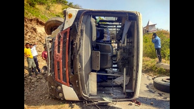 People stand near an overturned HRTC bus at Arki in Solan district on Friday. (PTI)