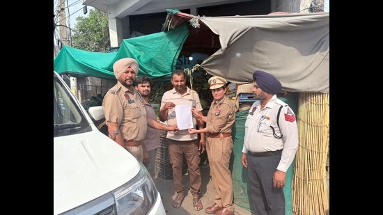 Traffic police issuing notice to a shopkeeper for illegal encroachment in Ludhiana on Friday. (HT Photo)
