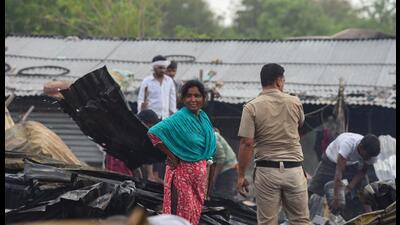 People salvage charred belongings from a site where a massive fire erupted at a slum area in Sector-52A near Ardee Mall in Gurugram on Saturday. (Parveen Kumar/Hindustan Times)