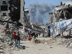 Smoke billows to the north as Palestinians move with their belongings through Jabalia while fleeing the northern Gaza Strip towards Gaza City on May 19, 2025. 