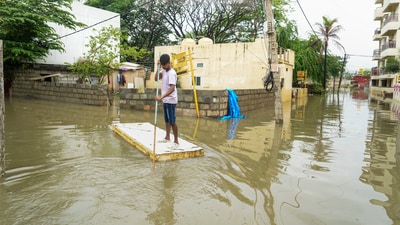A young man uses a makeshift boat to move across a waterlogged area after heavy rains, in Bengaluru. (PTI) A young man uses a makeshift boat to move across a waterlogged area after heavy rains, in Bengaluru. (PTI)
