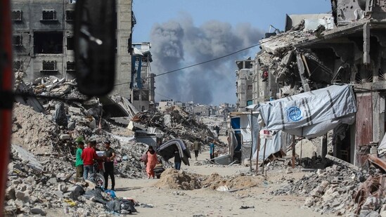 Smoke billows to the north as Palestinians move with their belongings through Jabalia while fleeing the northern Gaza Strip towards Gaza City on May 19, 2025. (AFP)