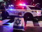A man, with an Israeli flag with a cross in the center, kneels next to emergency personnel working at the site where two Israeli embassy staff were shot dead near the Capital Jewish Museum in Washington.