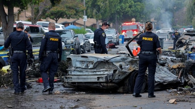 Emergency personnel work at the crash scene on a street, after a small civilian aircraft went down in a military neighborhood in San Diego (REUTERS)
