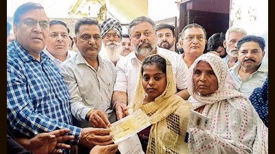 State BJP treasurer Gurdev Sharma Debi (left) hands over a chequer of  ₹1 lakh to the family of a victim who died after consuming spurious liquor in Ludhiana. (HT Photo)
