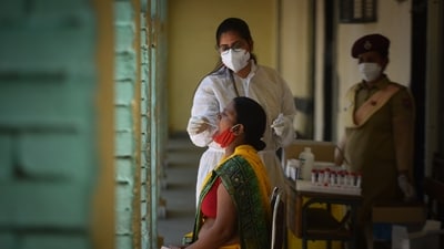 A health worker in PPE Coveralls collects a swab sample to test for Covid infection at a school in Janakpuri, New Delhi on May 26, 2021. (Sanchit Khanna/ Hindustan Times)