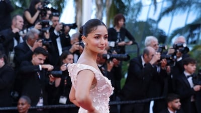 Alia Bhatt kept the makeup dewy with minimal glam and tied her hair into a neat bun, showcasing her gown. (Photo by Sameer AL-DOUMY / AFP) (AFP) Alia Bhatt kept the makeup dewy with minimal glam and tied her hair into a neat bun, showcasing her gown. (Photo by Sameer AL-DOUMY / AFP) (AFP)