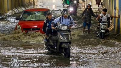 Commuters wade through a waterlogged road after heavy rains, in Bengaluru, Tuesday, May 20. (PTI) Commuters wade through a waterlogged road after heavy rains, in Bengaluru, Tuesday, May 20. (PTI)