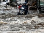 A man pushes his bike through a flooded street after heavy rain showers in Mumbai. A man pushes his bike through a flooded street after heavy rain showers in Mumbai.