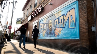 People walk by a portrait of George Floyd on the wall outside Unity Foods during the Rise and Remember event at George Floyd Square on his 5th death anniversary. (Getty Images via AFP)