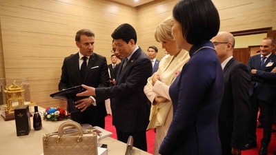France's President Emmanuel Macron (L) offers a decorative souvenir to Vietnam's President Luong Cuong (2nd L), as their respective wives Brigitte Macron (2nd R) and Nguyen Thi Minh Nguyet (R) look on during a state dinner at the International Convention Center in Hanoi on May 26, 2025. (Photo by Ludovic MARIN / AFP) (AFP) France's President Emmanuel Macron (L) offers a decorative souvenir to Vietnam's President Luong Cuong (2nd L), as their respective wives Brigitte Macron (2nd R) and Nguyen Thi Minh Nguyet (R) look on during a state dinner at the International Convention Center in Hanoi on May 26, 2025. (Photo by Ludovic MARIN / AFP) (AFP)