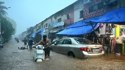 Commuters wade through a severely waterlogged road at Malabar Hill area following heavy rainfall, in Mumbai on Monday. (ANI) Commuters wade through a severely waterlogged road at Malabar Hill area following heavy rainfall, in Mumbai on Monday. (ANI)