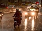 Commuters ride along a street as it rains in the Peshawar district of the Khyber Pakhtunkhwa province of Pakistan on May 27, 2025. 