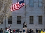 Demonstrators with signs stand around the John Harvard Statue in Harvard Yard after a rally was held against President Donald Trump's attacks on Harvard University 