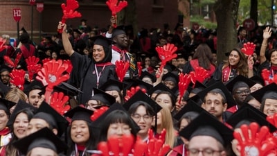 CAMBRIDGE, MASSACHUSETTS - MAY 29: Harvard graduates use plastic clappers to celebrate their accomplishments at the commencement ceremony in Harvard Yard on May 29, 2025 in Cambridge, Massachusetts. The joyous occasion unfolds amid escalating tensions between Harvard and the Trump administration, which has ordered the cancellation of federal contracts valued at approximately $100 million. Libby O'Neill/Getty Images/AFP (Photo by Libby O'Neill / GETTY IMAGES NORTH AMERICA / Getty Images via AFP) (Getty Images via AFP) CAMBRIDGE, MASSACHUSETTS - MAY 29: Harvard graduates use plastic clappers to celebrate their accomplishments at the commencement ceremony in Harvard Yard on May 29, 2025 in Cambridge, Massachusetts. The joyous occasion unfolds amid escalating tensions between Harvard and the Trump administration, which has ordered the cancellation of federal contracts valued at approximately $100 million. Libby O'Neill/Getty Images/AFP (Photo by Libby O'Neill / GETTY IMAGES NORTH AMERICA / Getty Images via AFP) (Getty Images via AFP)