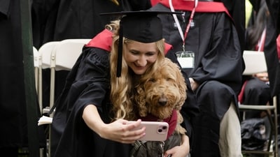CAMBRIDGE, MASSACHUSETTS - MAY 29: Katie Derr of Las Vegas poses with her service dog, Stich, to celebrate commencement on May 29, 2025, in Cambridge, Massachusetts. The joyous occasion unfolds amid escalating tensions between Harvard and the Trump administration, which has ordered the cancellation of federal contracts valued at approximately $100 million. Libby O'Neill/Getty Images/AFP (Photo by Libby O'Neill / GETTY IMAGES NORTH AMERICA / Getty Images via AFP) (Getty Images via AFP) CAMBRIDGE, MASSACHUSETTS - MAY 29: Katie Derr of Las Vegas poses with her service dog, Stich, to celebrate commencement on May 29, 2025, in Cambridge, Massachusetts. The joyous occasion unfolds amid escalating tensions between Harvard and the Trump administration, which has ordered the cancellation of federal contracts valued at approximately $100 million. Libby O'Neill/Getty Images/AFP (Photo by Libby O'Neill / GETTY IMAGES NORTH AMERICA / Getty Images via AFP) (Getty Images via AFP)