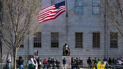 Demonstrators with signs stand around the John Harvard Statue in Harvard Yard after a rally was held against President Donald Trump's attacks on Harvard University (AFP) Demonstrators with signs stand around the John Harvard Statue in Harvard Yard after a rally was held against President Donald Trump's attacks on Harvard University (AFP)