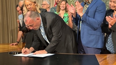 On Tuesday, May 27, 2026, Hawaii Governor Josh Green, joined by lawmakers and supporters in Honolulu, signed legislation increasing the state’s tax on hotel rooms and other short-term accommodations. Hawaii becomes first US state to implement Gree Fee. (AP Photo/Audrey McAvoy) (AP) On Tuesday, May 27, 2026, Hawaii Governor Josh Green, joined by lawmakers and supporters in Honolulu, signed legislation increasing the state’s tax on hotel rooms and other short-term accommodations. Hawaii becomes first US state to implement Gree Fee. (AP Photo/Audrey McAvoy) (AP)
