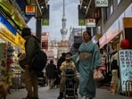 This picture taken on February 21, 2025 shows people walking past shops in the Asakusa area as the 634m-high (2,080 ft.) 