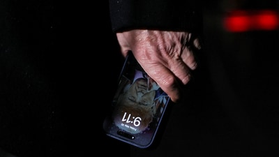 U.S. President Donald Trump holds a mobile phone with his image on it (REUTERS)