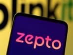 Zepto logo is seen on smartphone in front of Blinkit logo in this illustration. 