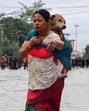 A woman carrying her pet dog wades through a flooded street following heavy rainfall in Imphal East in Manipur on Sunday. (AFP)