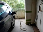 A car gets charged at an electric vehicle charging station at a residential building parking area in Mumbai.