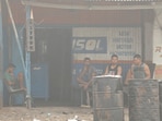 People sit outside a truck repair shop in the town of Byrnihat, ranked world's most polluted metropolitan area by Swiss Group IQAir, in Meghalaya