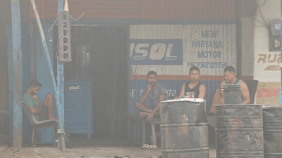 People sit outside a truck repair shop in the town of Byrnihat, ranked world's most polluted metropolitan area by Swiss Group IQAir, in Meghalaya (Reuters File)