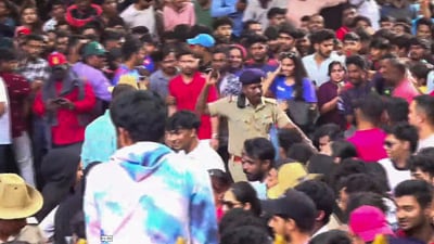 A security personnel tries to manage the crowd of fans gathered for the felicitation of IPL 2025 winning RCB team, near the Chinnaswamy Stadium (PTI)