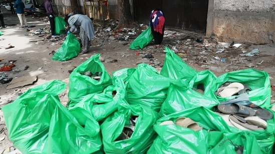 Bengaluru: Workers remove footwears lying near the Gate No. 7 of the Chinnaswamy Stadium, a day after the stampede. (PTI)