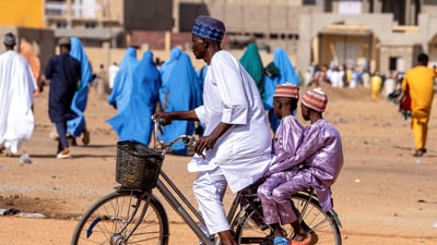 Children are seen riding with their father on a bicycle after the Eid al-Adha prayer in Kano, Nigeria, June 6, 2025. (REUTERS)