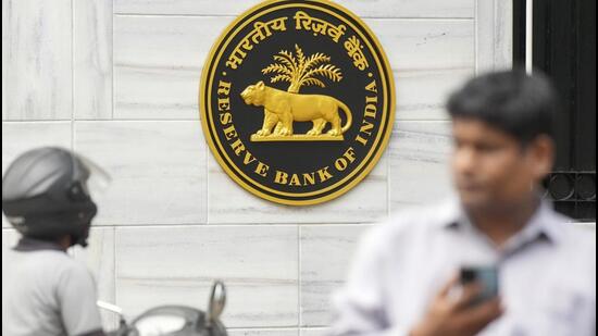 People walk past the Reserve Bank of India (RBI) logo outside its headquarters, in Mumbai. (PTI)