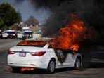 Clashes intensified overnight, with fires, fireworks, and anti-ICE slogans seen on burned-out vehicles. In pic: A car burns in flames during a standoff between police and protesters following multiple detentions by Immigration and Customs Enforcement (ICE), in the Los Angeles County city of Compton.