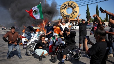 Democrats, including Rep Nanette Barragán, accused Trump of targeting peaceful protests for political purposes. In pic: People hold Mexican flags and gesture next to a car in flames. (REUTERS)