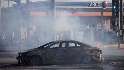 A destroyed car sits on the road during a standoff between police and protesters following multiple detentions by Immigration and Customs Enforcement (ICE), in the Los Angeles County city of Compton, California, on June 7. (REUTERS)