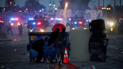Helmeted troops with automatic weapons were seen near LA City Hall ahead of more protests, according to ABC News. In pic: A protester fires a firework during a standoff between police and protesters in LA. (REUTERS)