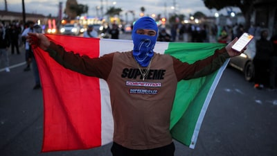 Dozens of migrants were arrested in Los Angeles, a city with a significant Latino population, sparking outrage. In pic: A protester holds a Mexican flag during a standoff between police and protesters in the Los Angeles County city of Compton. (REUTERS)