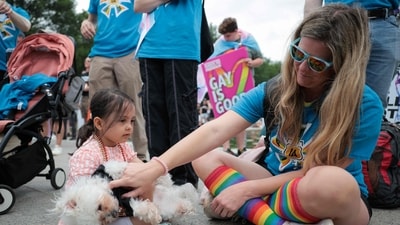 Dele Zeitouni, 4, and Sarah Fales shared a joyful moment as they petted a dog during the WorldPride International Rally and March on Washington for Freedom at the Lincoln Memorial on June 8, 2025. (Photo by Kayla Bartkowski / GETTY IMAGES NORTH AMERICA / Getty Images via AFP) (Getty Images via AFP)