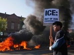 A protester holds a sign as a Waymo taxi burns near the metropolitan detention center of downtown Los Angeles, Sunday, June 8, 2025, following last night's immigration raid protest. (AP Photo/Eric Thayer) A protester holds a sign as a Waymo taxi burns near the metropolitan detention center of downtown Los Angeles, Sunday, June 8, 2025, following last night's immigration raid protest. (AP Photo/Eric Thayer)