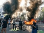 Cars burn behind protesters during a demonstration in Los Angeles, California, US, on Sunday, June 8, 2025. (Photographer: Kyle Grillot/Bloomberg) Cars burn behind protesters during a demonstration in Los Angeles, California, US, on Sunday, June 8, 2025. (Photographer: Kyle Grillot/Bloomberg)
