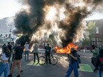 Cars burn behind protesters during a demonstration in Los Angeles, California, US, on Sunday, June 8, 2025. (Photographer: Kyle Grillot/Bloomberg) Cars burn behind protesters during a demonstration in Los Angeles, California, US, on Sunday, June 8, 2025. (Photographer: Kyle Grillot/Bloomberg)