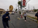 Residents who saw cleanup going on stopped to help in the parking lot of a shopping center by Dale’s Donuts, a day after clashes between protesters and law enforcement following multiple detentions by Immigration and Customs Enforcement (ICE), in Compton, California, U.S., June 8, 2025. (REUTERS/Jill Connelly)