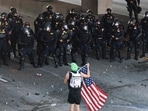 California Highway Patrol (CHP) officers stand guard as a person holds up an American flag while blocking the 101 freeway on June 08, 2025 in Los Angeles, California. (Photo by MARIO TAMA / GETTY IMAGES NORTH AMERICA / Getty Images via AFP) California Highway Patrol (CHP) officers stand guard as a person holds up an American flag while blocking the 101 freeway on June 08, 2025 in Los Angeles, California. (Photo by MARIO TAMA / GETTY IMAGES NORTH AMERICA / Getty Images via AFP)