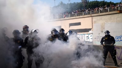 Police are visible through smoke on the 101 Freeway near the Metropolitan Detention Centre following protests against immigration raids on Sunday. (AP)