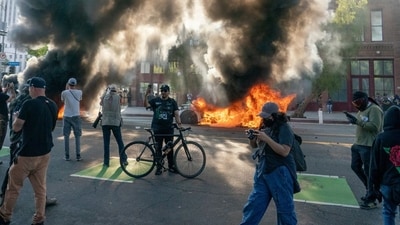 Cars burn behind protesters during a demonstration in Los Angeles, California, US, on Sunday, June 8, 2025. (Photographer: Kyle Grillot/Bloomberg) (Bloomberg) Cars burn behind protesters during a demonstration in Los Angeles, California, US, on Sunday, June 8, 2025. (Photographer: Kyle Grillot/Bloomberg) (Bloomberg)