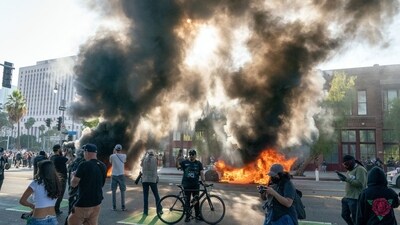 Cars burn behind protesters during a demonstration in Los Angeles, California, US, on Sunday, June 8, 2025. (Photographer: Kyle Grillot/Bloomberg) (Bloomberg) Cars burn behind protesters during a demonstration in Los Angeles, California, US, on Sunday, June 8, 2025. (Photographer: Kyle Grillot/Bloomberg) (Bloomberg)