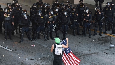 California Highway Patrol (CHP) officers stand guard as a person holds up an American flag while blocking the 101 freeway on June 08, 2025 in Los Angeles, California. (Photo by MARIO TAMA / GETTY IMAGES NORTH AMERICA / Getty Images via AFP) (Getty Images via AFP) California Highway Patrol (CHP) officers stand guard as a person holds up an American flag while blocking the 101 freeway on June 08, 2025 in Los Angeles, California. (Photo by MARIO TAMA / GETTY IMAGES NORTH AMERICA / Getty Images via AFP) (Getty Images via AFP)