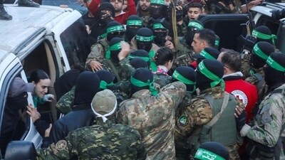 Palestinian Hamas militants hand over hostages kidnapped during the October 7, 2023, attack on Israel by Hamas, to members of the Red Cross as part of a ceasefire and a hostages-prisoners swap deal between Hamas and Israel, in Gaza City, January 19, 2025. (Reuters) (Reuters file photo.)